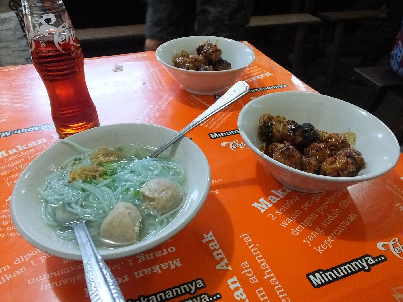 Semangkuk bakso dan es teh di meja warung makan di Malang